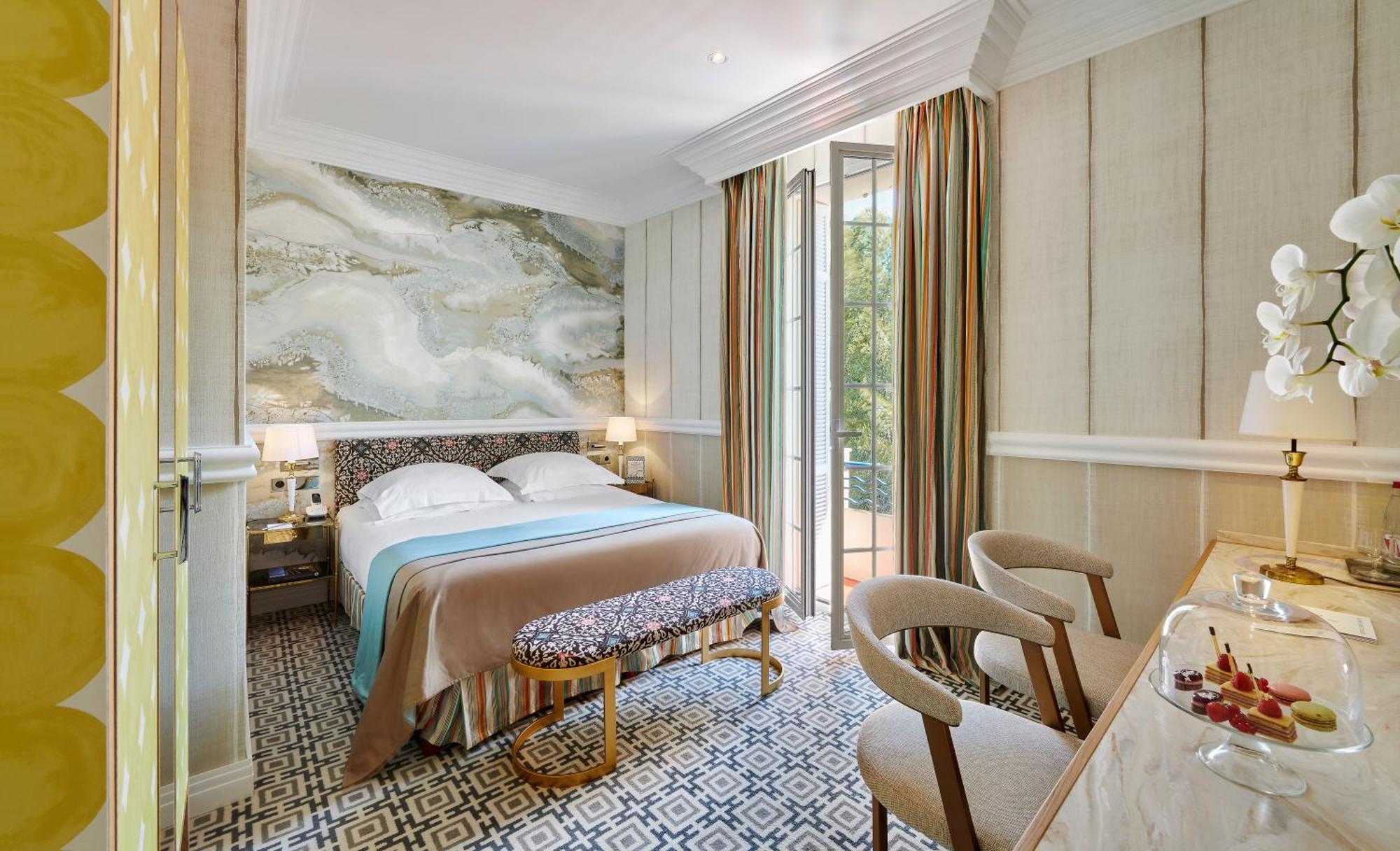 una camera da letto con un letto e un balcone con un tavolo di Hôtel de Paris Saint-Tropez a Saint-Tropez